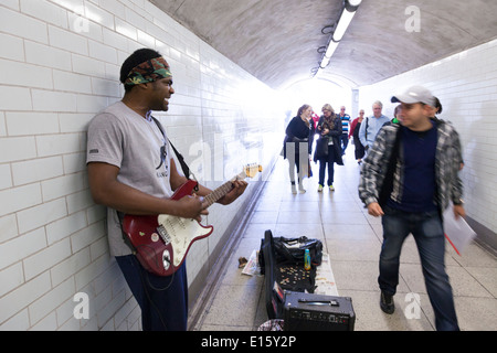 Busker playing electric guitar in underpass. Stock Photo