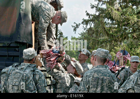 US Army soldier from the Old Guard distribute flags to be placed in front of grave sites in honor of Memorial Day at Arlington National Cemetery May 22, 2014 in Arlington, Virginia. Stock Photo