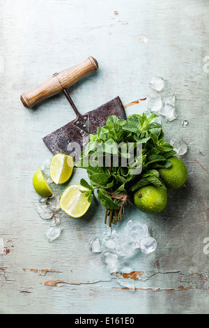 Ingredients for making mojitos. Ice cubes, mint leaves and lime on blue background Stock Photo