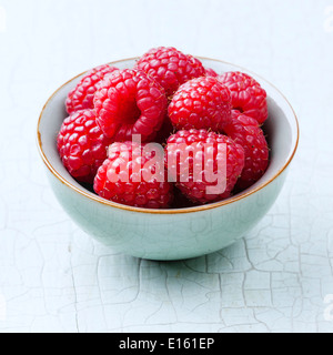 Raspberries in bowl on blue background Stock Photo