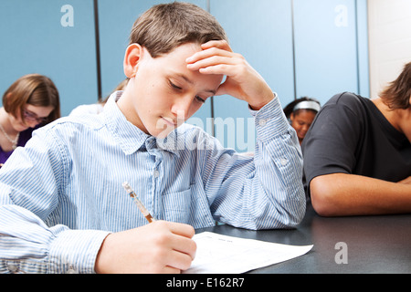 Adolescent middle school boy concentrats on a standardized test in school.  Stock Photo