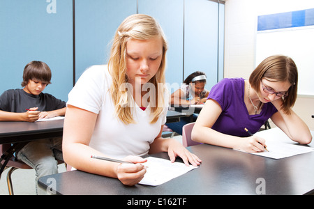 Pretty blond girl taking a test with her high school class.  Stock Photo