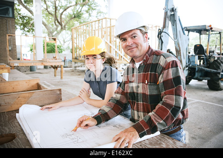 Engineer going over blueprints with a student on the construction site.  Stock Photo