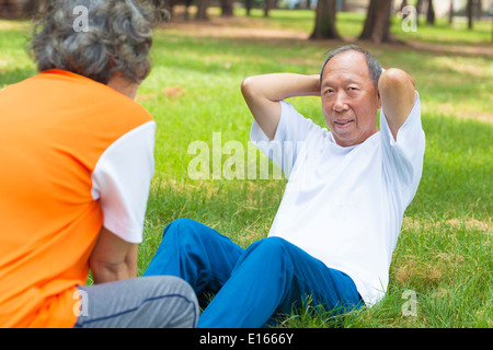 senior grandfather doing sit-ups in the park Stock Photo