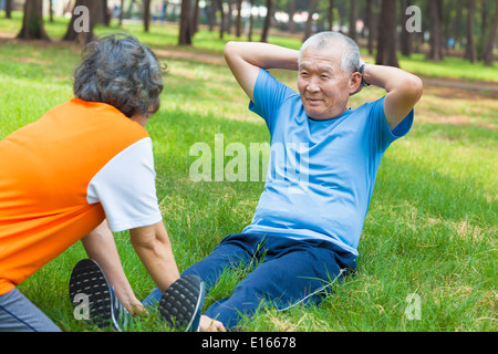 asian senior grandfather doing sit-ups in the park Stock Photo