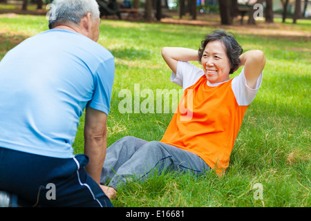 smiling senior grandmother doing sit-ups in the park Stock Photo