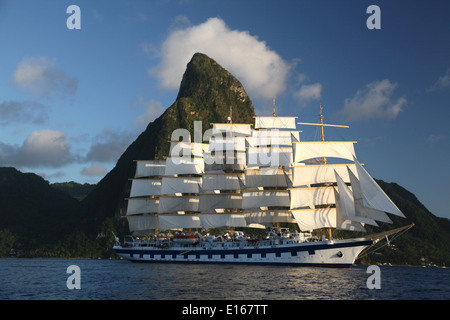 A sailing clipper ship in full sail,leaves port in St. Lucia and passes under the iconic Caribbean mountain Stock Photo