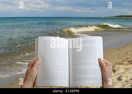 woman reading a book on the beach Stock Photo