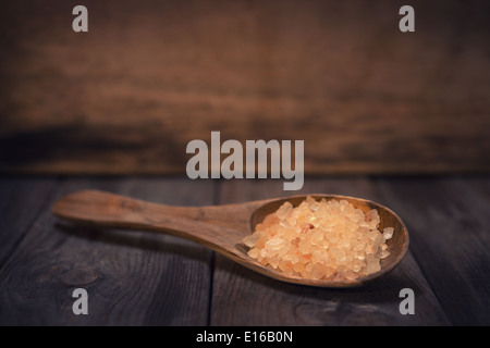Natural shower salt on wooden spoon, wood background with blank copy space. Stock Photo