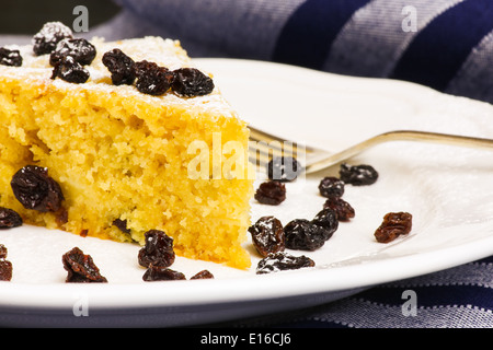 Apple vanilla ginger cake with black currants on white plate and silver fork striped tablecloth Stock Photo