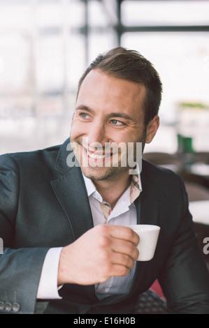 Handsome smiling man drinking espresso in cafe Stock Photo