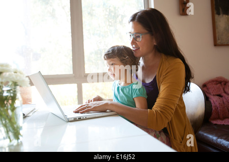 Mother and daughter sitting in front of laptop Stock Photo