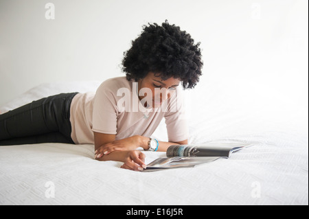 Young woman reading magazine on bed, Milano, Italy Stock Photo