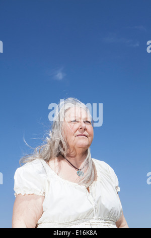 Portrait of middle aged woman standing against blue sky Stock Photo