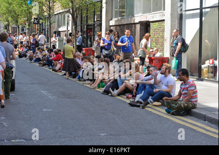 People making the best of the British weather sitting on the pavement and eating spicy food bought from Asian restaurants. Stock Photo