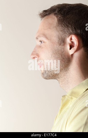 Smiling Young Caucasian Man profile portrait above gray wall Stock Photo