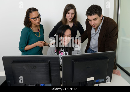 Office workers discussing a project while looking at a computer screen Stock Photo