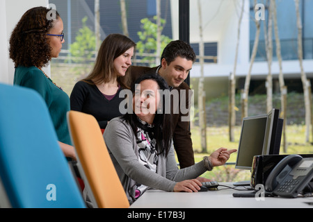 Office workers discussing a project while looking at a computer screen Stock Photo