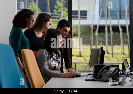 Office workers discussing a project while looking at a computer screen Stock Photo