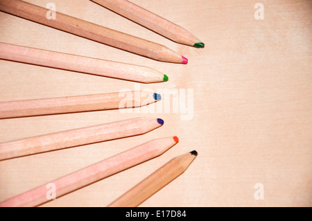 Seven wooden colored pencils over a wood surface Stock Photo