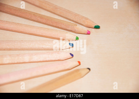 Seven wooden colored pencils over a wood surface Stock Photo
