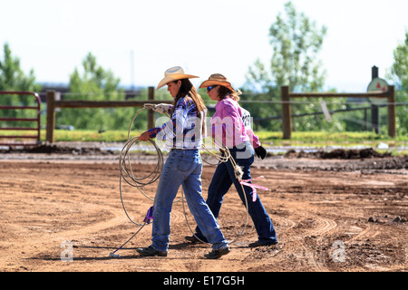 Two cowgirls practice their roping skills outside the rodeo arena prior to the Team Roping Event Stock Photo