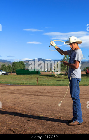 A young cowboy practices his roping skills outside the rodeo arena prior to the Team Roping Event at a rodeo Stock Photo