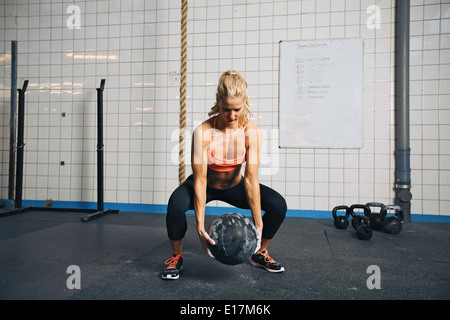 Fit and strong female athlete working out with a medicine ball to get better core strength and stability. Woman doing exercise. Stock Photo