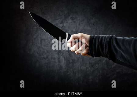 Evil man with shiny knife - a killer person with sharp knife about to commit a homicide, murder scenery. Stock Photo