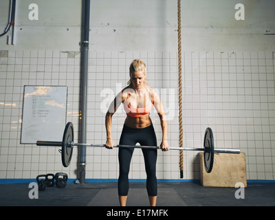 Fit and attractive caucasian female holding a barbell in her hands. Crossfit woman lifting heavy weights in gym. Stock Photo