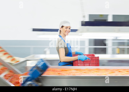 Portrait of confident worker carrying crate in food processing plant Stock Photo