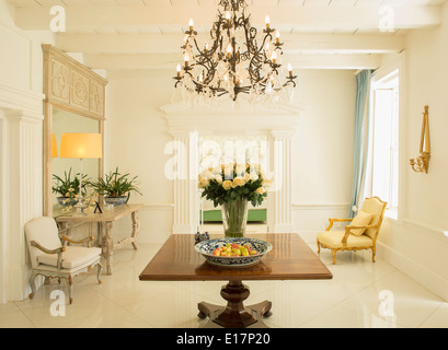 Chandelier over rose bouquet on table in luxury foyer Stock Photo