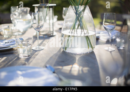 Vase and place settings on sunny patio table Stock Photo