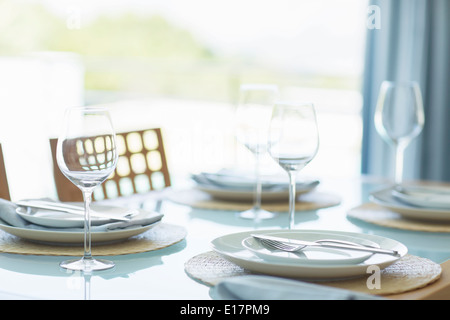 Place settings on table in sunny dining room Stock Photo