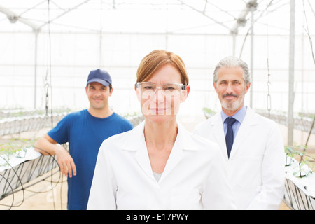 Portrait of confident scientists and worker in greenhouse Stock Photo