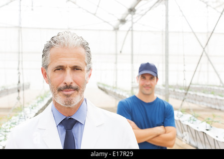 Portrait of confident scientist and worker in greenhouse Stock Photo