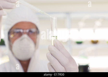 Scientist in clean suit using pipette and test tube in laboratory Stock Photo