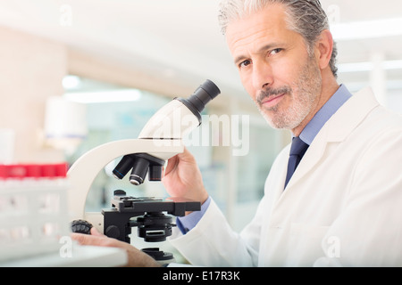Portrait of confident scientist using microscope in laboratory Stock Photo