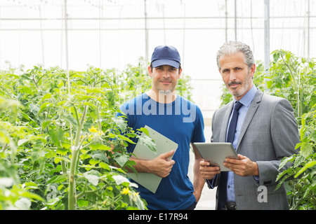 Portrait of confident business owner and worker in greenhouse Stock Photo