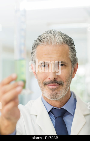 Portrait of confident scientist holding tube with green liquid Stock Photo