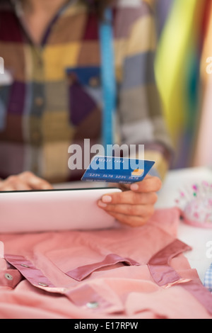 Closeup on seamstress with credit card using tablet pc Stock Photo