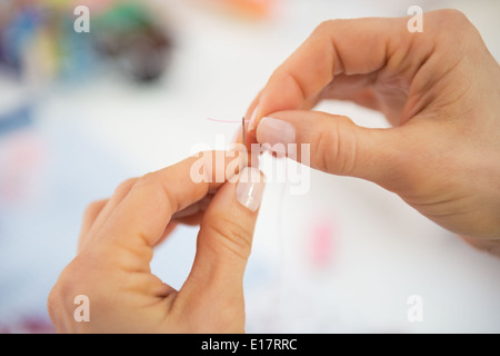 Closeup on seamstress threading needle Stock Photo