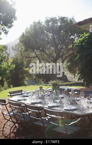Place settings on sunny rural patio table Stock Photo
