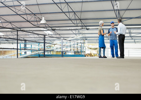 Supervisor and workers talking in food processing plant Stock Photo