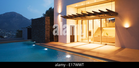 Illuminated modern house overlooking swimming pool Stock Photo