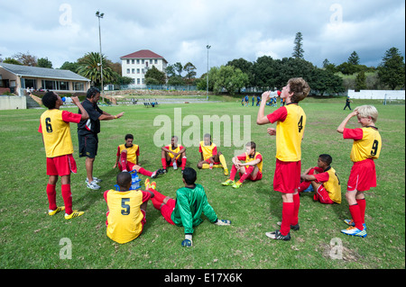Coach instructing junior football team during the break, Cape Town, South Africa Stock Photo