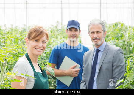 Portrait of confident business owner and workers in greenhouse Stock Photo
