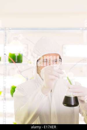 Scientist in clean suit with beaker in laboratory Stock Photo