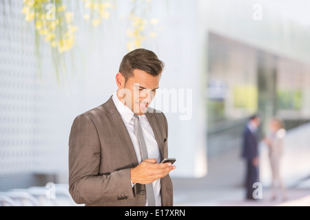 Businessman texting with cell phone outdoors Stock Photo
