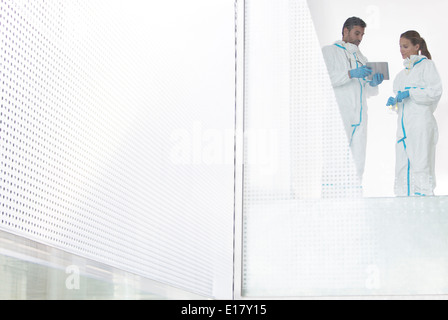 Scientists in clean suits using digital tablet Stock Photo